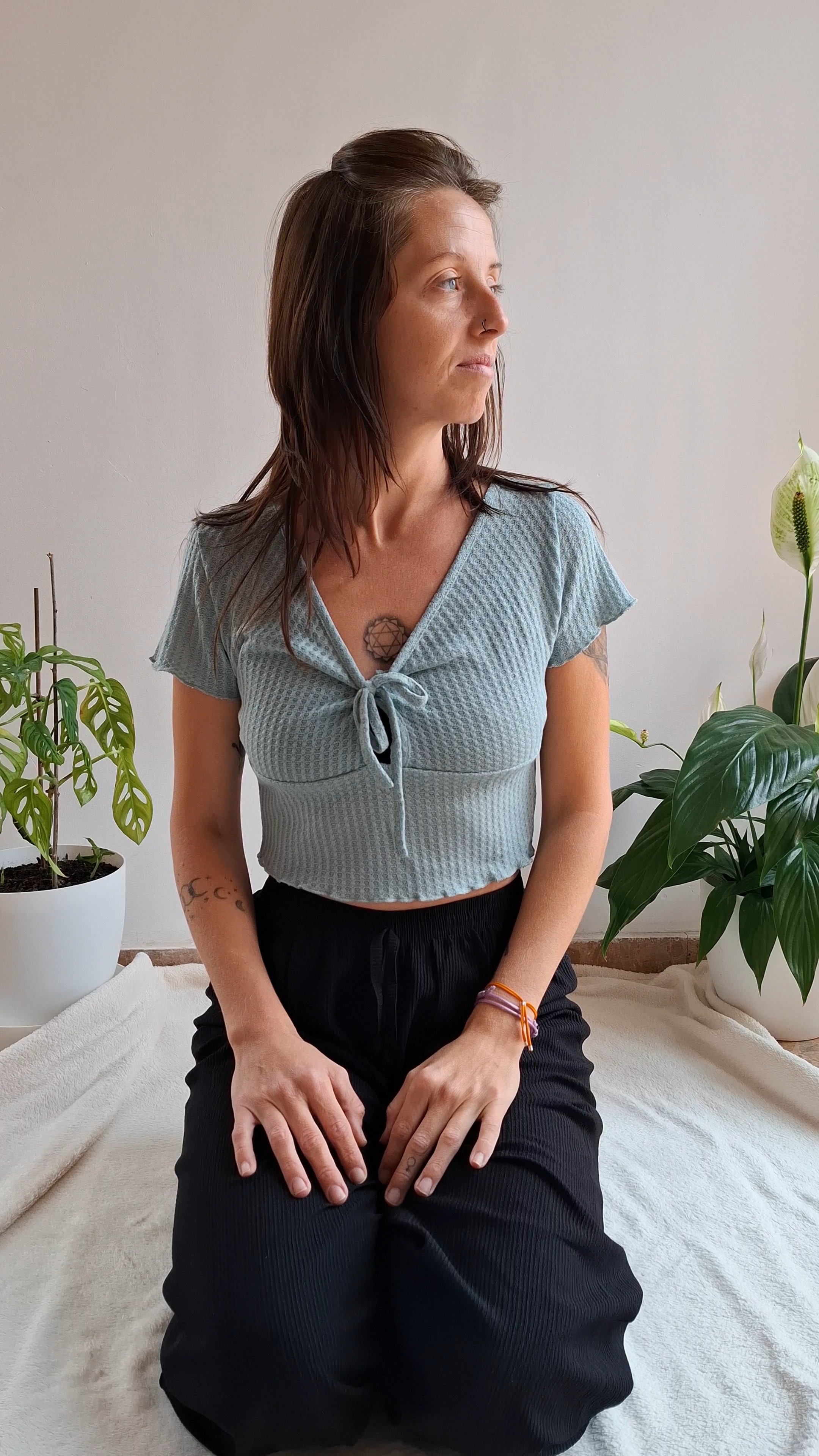 marta pimentel. crea tu yoga. Imagen de Marta Pimentel en pose calmada y relajada, en pose de meditación rodeada de plantas en su espacio de yoga.